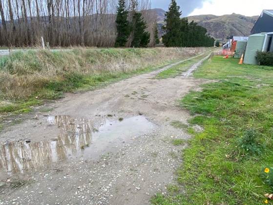 A dirt road with a puddle of water

Description automatically generated