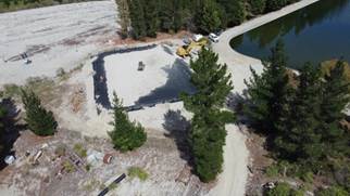 A construction site with a pond and trees

Description automatically generated