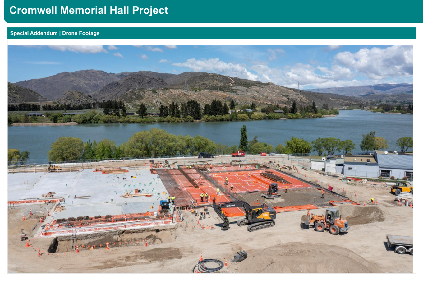 A construction site with a lake and mountains in the background

Description automatically generated