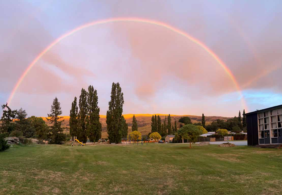A rainbow over a field

Description automatically generated